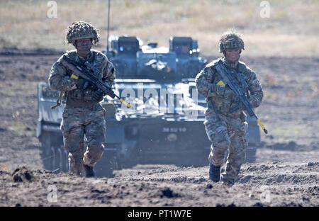 Augustdorf, Germany. 5th Oct 2018. Soldiers running ahead of a tank during a presentation on a military training area near Augustdorf. German and British soldiers took part in the presentation. Defence Minister von der Leyen and her British counterpart signed a 'Joint Vision Statement', a bilateral declaration on closer cooperation in security and defence matters. Photo: Ralf Hirschberger/dpa Credit: dpa picture alliance/Alamy Live News Stock Photo