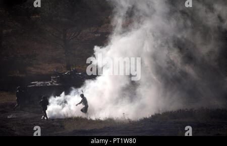 Augustdorf, Germany. 5th Oct 2018. Soldiers running ahead of a tank during a presentation on a military training area near Augustdorf. German and British soldiers took part in the presentation. Defence Minister von der Leyen and her British counterpart signed a 'Joint Vision Statement', a bilateral declaration on closer cooperation in security and defence matters. Photo: Ralf Hirschberger/dpa Credit: dpa picture alliance/Alamy Live News Stock Photo