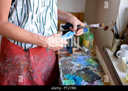 Female painter in her atelier, paint tube and paintbrushes Stock Photo