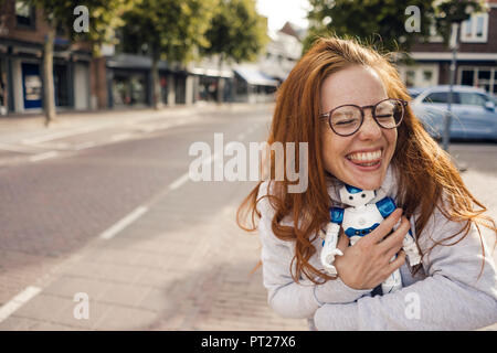 Redheaded woman hugging toy robot Stock Photo