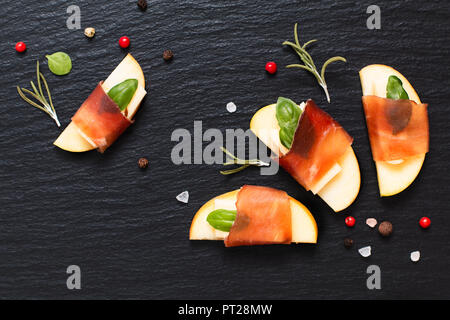 Food holiday appetizer  Apple, Brie and Dried Cured beefs Bresaola on black slate plate Stock Photo