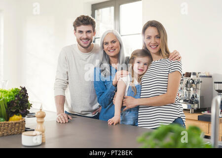 Happy three generations family standing in kitchen Stock Photo
