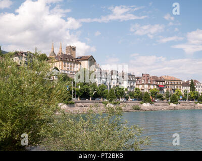 Neuchatel waterfront with the castle showing through and trees in the foreground in the spring, Switzerland Stock Photo