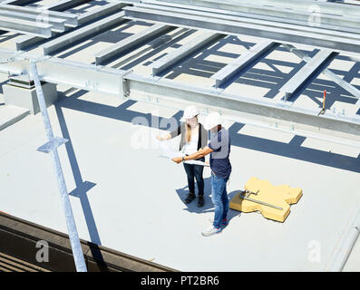 Worker and architect looking at blueprint on construction site Stock Photo