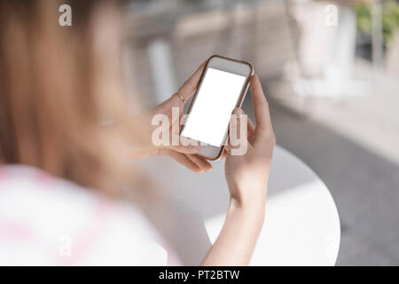 Young woman sitting in coffee shop, using smartphone Stock Photo