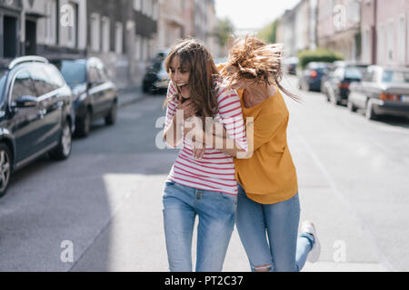 Two girlfriends having fun in the city, running Stock Photo