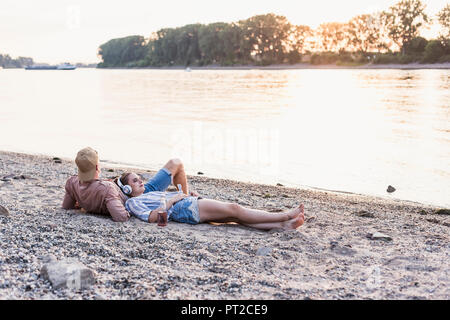 Young couple relaxing at the riverbank at sunset Stock Photo