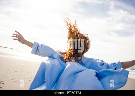 Woman running on the beach with arms out, rear view Stock Photo