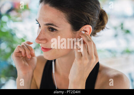 Young businesswoman sitting in coffee shop, taking a break, listening music Stock Photo