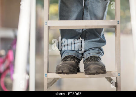 Man standing on ladder, partial view Stock Photo