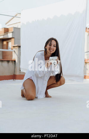 Portrait of young woman with camera on roof terrace Stock Photo