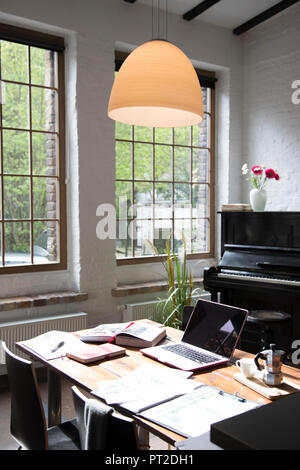 Home office with piano in background at comfortable loft apartment Stock Photo