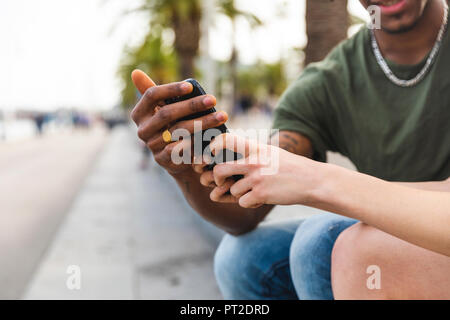 Hands of multicultural young couple holding smartphone, close-up Stock Photo