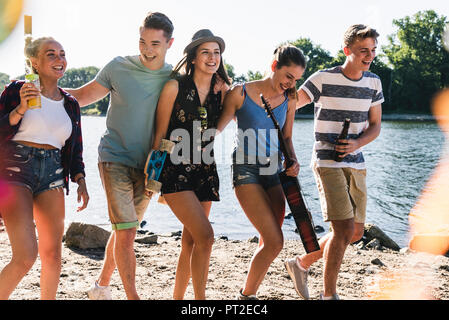 Group of happy friends walking arm in arm at the riverside Stock Photo
