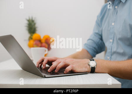 Businessman working on his laptop at home, partial view Stock Photo