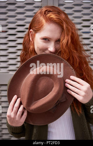 Portrait of smiling redheaded woman with brown hat Stock Photo