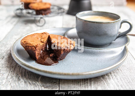 Chocolate muffin with liquid chocolate on plate with coffee cup Stock Photo