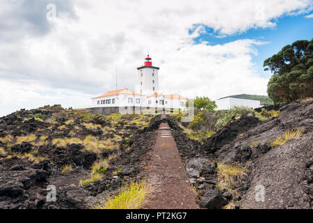 Lighthouse of Piedade on rocky shore built on lava rock Stock Photo