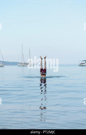 Man doing handstand in water Stock Photo