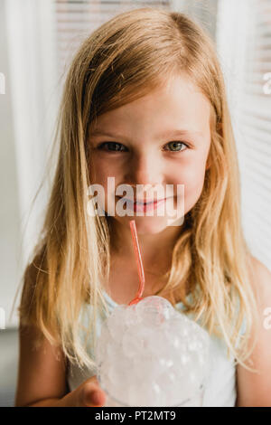 Portrait of blond little girl blowing milk bubbles Stock Photo