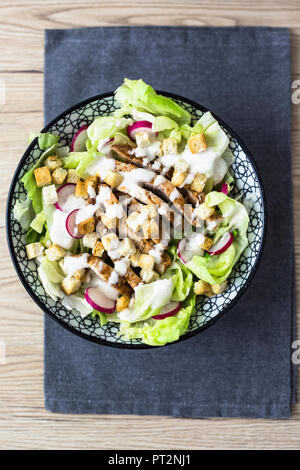 Bowl of Caesar salad with meat and red radish