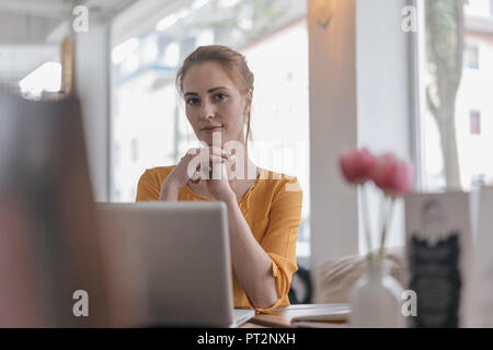 Young woman sitting in coworking space,using laptop Stock Photo