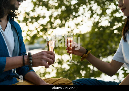Close-up of couple clinking champagne glasses at a tree Stock Photo