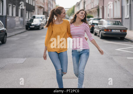 Two girlfriends having fun in the city, walking arm in arm Stock Photo