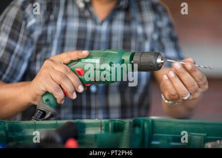 Man's hands holding electric drill Stock Photo