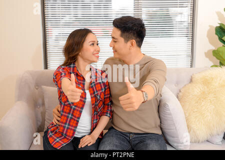 love, family and happiness concept - smiling happy couple at home showing thumbs up Stock Photo