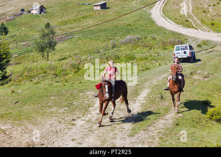 MIKULICZYN, UKRAINE - SEPTEMBER 14, 2018: Young riders horsemen gallop across the Starishora mountain valley, Carpathian Mountains. Stock Photo