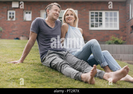 Smiling mature couple sitting in garden of their home Stock Photo