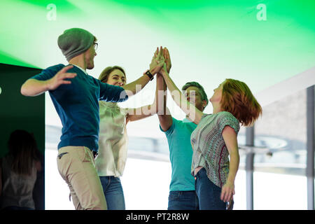 Happy business people high-fiving in office, jumping for joy Stock Photo