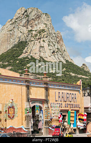 The massive monolith rock called the Pena de Bernal towners over the market in the beautiful colonial village of Bernal, Queretaro, Mexico. Bernal is a quaint colonial town known for the Pena de Bernal, a giant monolith which dominates the tiny village is the third highest on the planet. Stock Photo