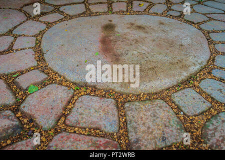 Vintage grungy gray pavement of cobblestones in a circle patterned background. Pavement of granite stone in organized arrangement background. Stock Photo