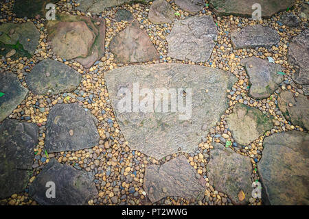 Vintage nature cobblestone and pebbles pavement in disorganized arrangement pattern background. Paving blocks made of nature asymmetrical stone backgr Stock Photo