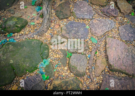 Vintage nature cobblestone and pebbles pavement in disorganized arrangement pattern background. Paving blocks made of nature asymmetrical stone backgr Stock Photo