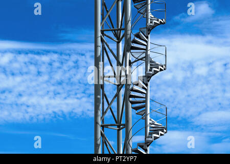 Steel spiral staircase against a blue sky that seems to lead to the sky Stock Photo