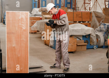 the storekeeper marks the arrival on the tablet. man driving a forklift through a warehouse in a factory. driver in uniform and protective helmet. the concept of logistics and storage Stock Photo