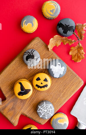 Halloween scary cookies with pumpkin on wooden cut board. pattern Bat , patina, ghosts and spiders. Red color background, top view Stock Photo