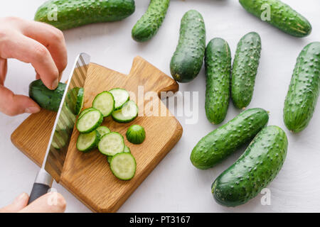 Mans hands cutting cucumbers for detox water. Top view. Process of preparing energy cocktail Stock Photo