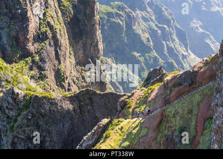 Three people descenging the steps on the trail from Pico Ruivo to Pico do Areeiro, Funchal, Madeira region, Portugal, Stock Photo