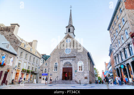 QUEBEC CITY, CANADA - AUG 21, 2012: Tourists meander the cobblestone streets of Place Royale in Old Quebec city, in front of Notre-Dame-des-Victoires  Stock Photo