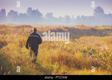 A man walking along through the field early in the morning Stock Photo
