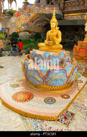 Golden sitting statue of Lord Buddha, sitting in a lotus, decorated with beautiful, colorful mosaic tiles at the entrance of at Pha Sorn Kaew, in Khao Stock Photo