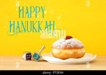 Image of jewish holiday Hanukkah with wooden dreidels (spinning top) and donut on the table Stock Photo