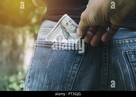 Close-up of a the hand of thief stealing money from a woman. Thief stealing money from back pocket of a woman. Stock Photo
