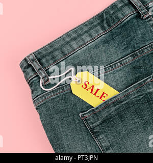 Concept of sale black Friday and cyber Monday discounts tag with blue jeans on pastel pink background. Copy space, flat lay, square format Stock Photo