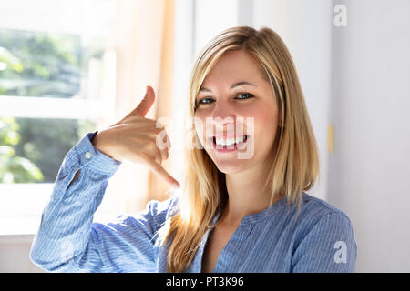 Portrait Of A Happy Young Businesswoman Making Call Me Gesture Stock Photo