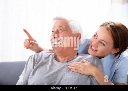 Close-up Of A Happy Female Nurse Pointing At Something To Senior Man Stock Photo